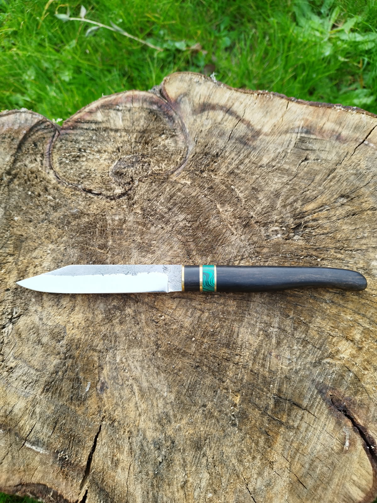 Couteau en bois noir (ébène de macassar) avec du laiton et de la pierre reconstituée (la malachite). La lame est en acier inoxydable.